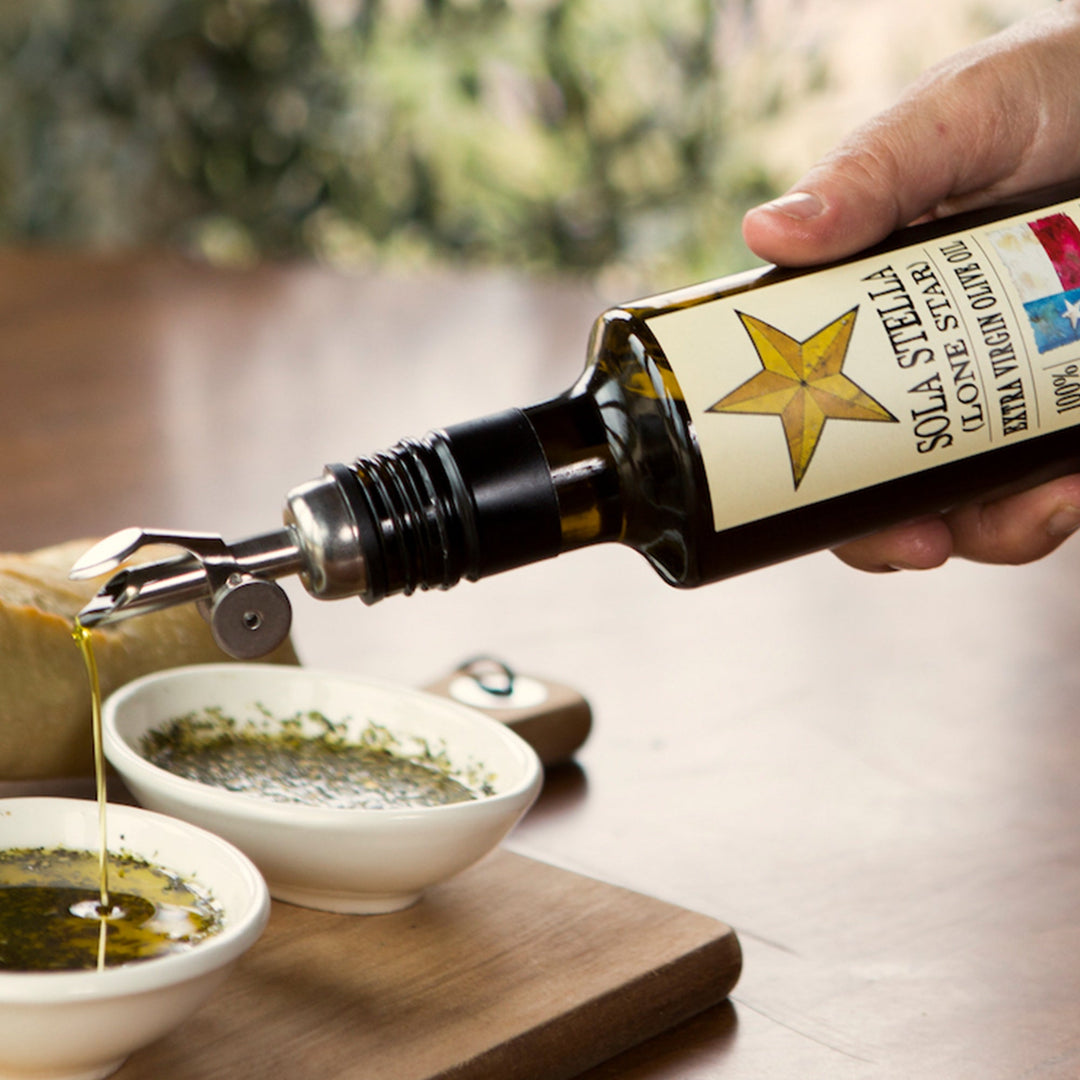 Sola Stella Extra Virgin Olive Oil poured through a metal spout into a shallow dipping bowl.